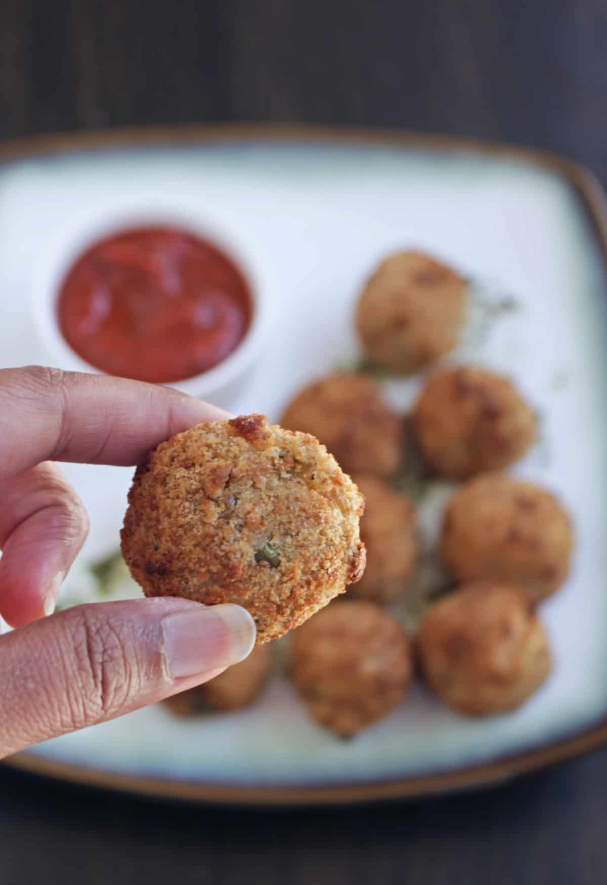 Holding an arancini ball in hand and more arancini in background