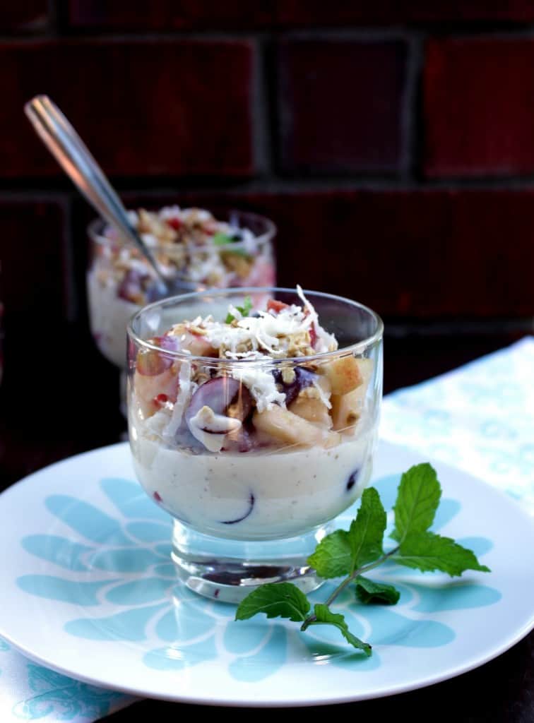  Mexican Fruit Salad in two bowls on a plate with mint leaves on the side.