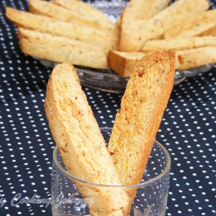 Walnut Biscotti in a glass cup with some in a plate in the background