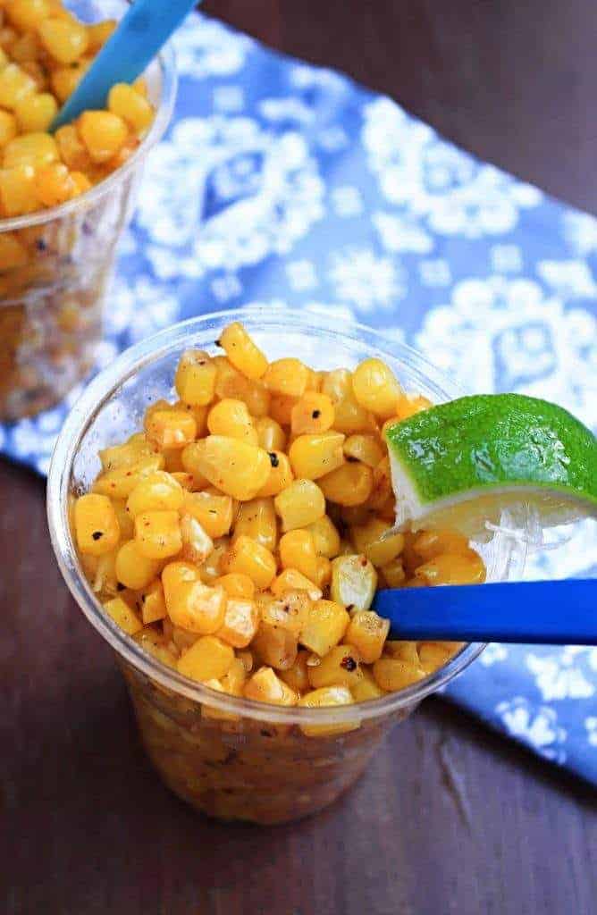 Buttered Sweet Corn Salad in a plastic cup with a slice of lemon on top