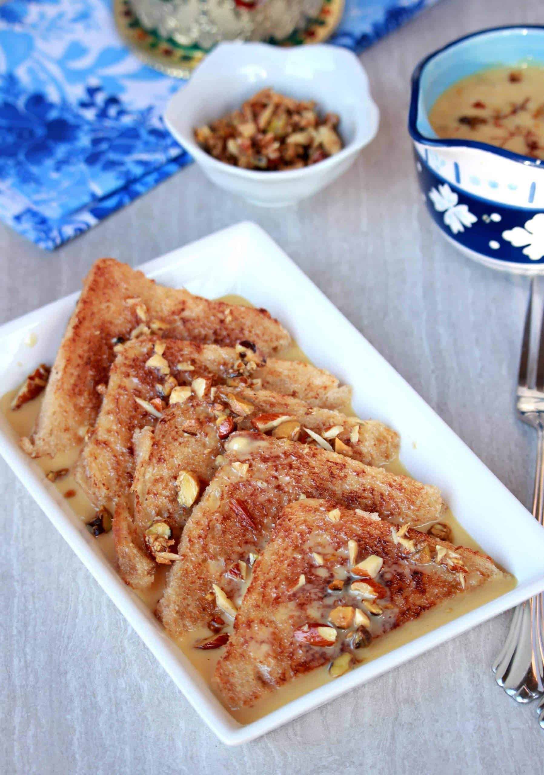 fried bread pieces in a white plate topped with nuts