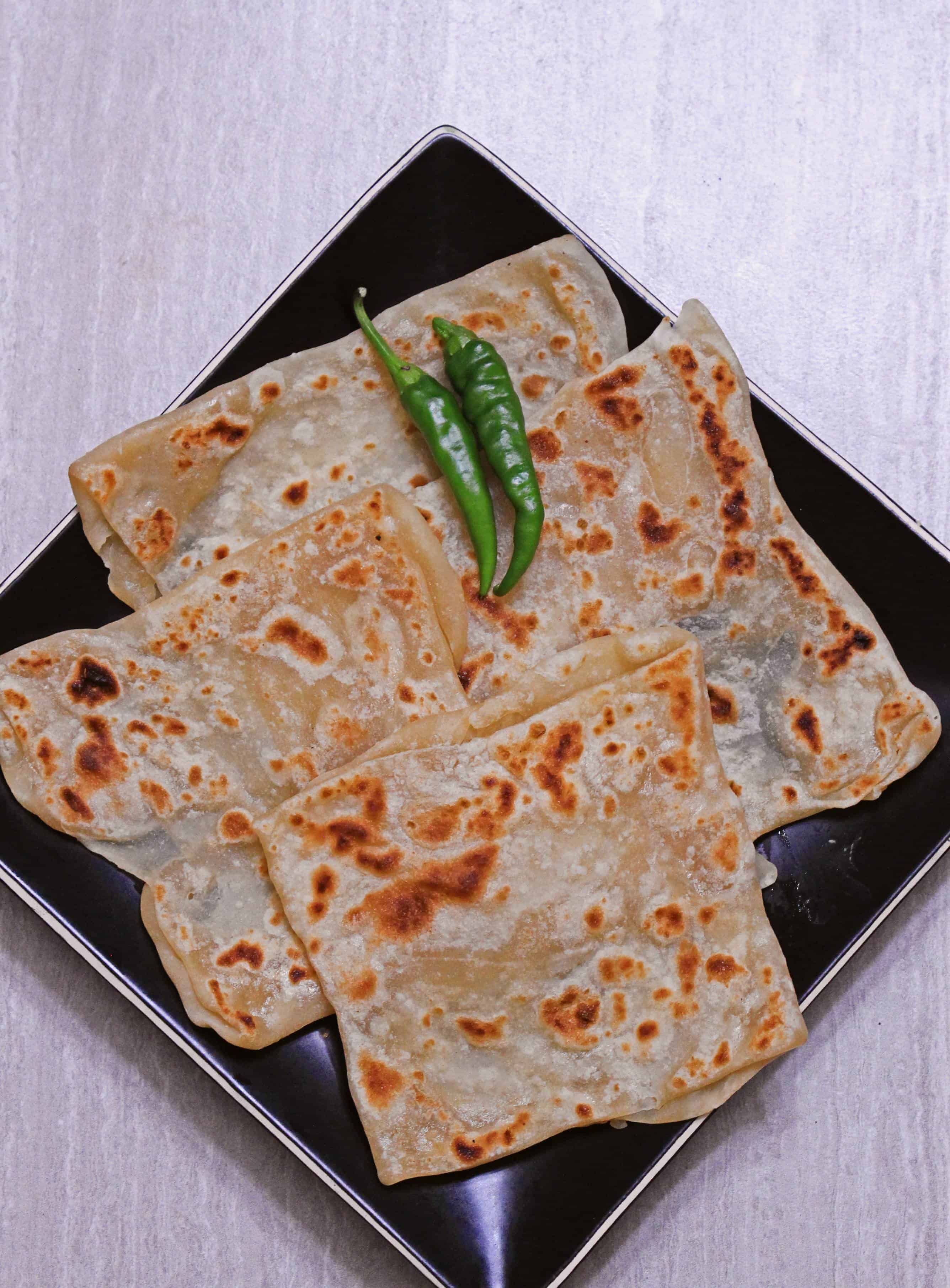 Veechu Parotta in a black plate with green chillies